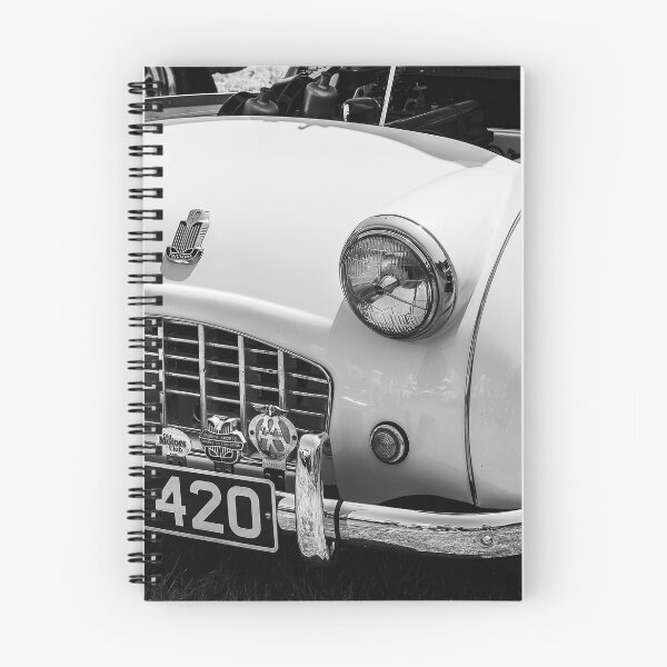 Item preview, A black and white image of the front of a white 1950s Triumph TR3 on display at a car show designed and sold by Graham Cornall.