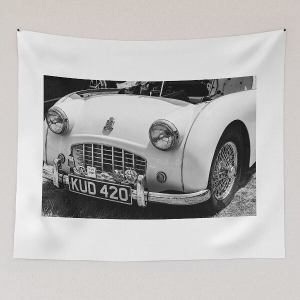 Item preview, A black and white image of the front of a white 1950s Triumph TR3 on display at a car show designed and sold by Graham Cornall.