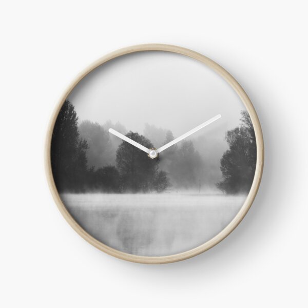 Trees disappearing in morning fog above the lake Clock