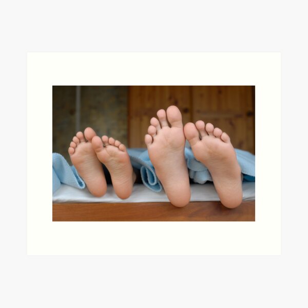 Two children (6-12) lying in bed, focus on feet, close-up Art Print