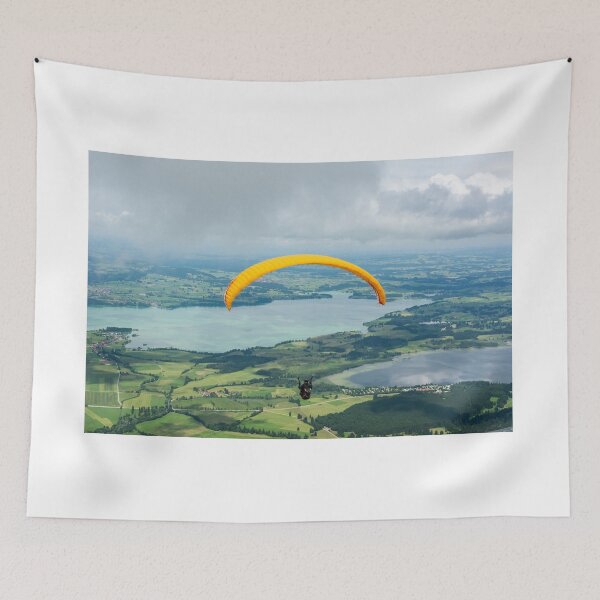 Item preview, A paraglider flying over Forggensee and Bannwaldsee lakes in Bavaria, Germany designed and sold by AlizadaStudios.