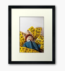 Doll resting on measuring tape Framed Print