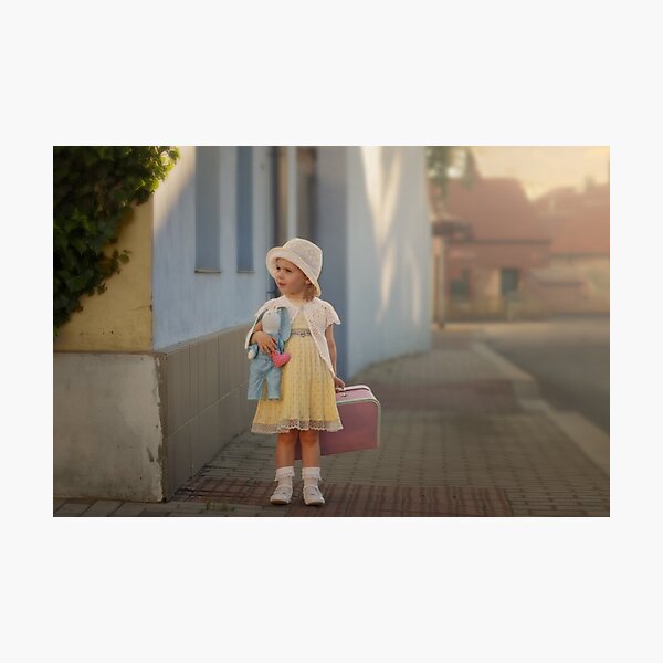Cute little girl in a yellow dress with a blue toy-rabbit and a pink suitcase walking down the street of the city. Retro style. Photographic Print