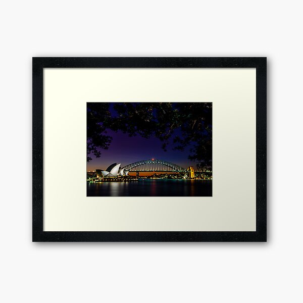 Sydney Harbour Bridge and Sydney Opera House at night framed by trees Framed Art Print