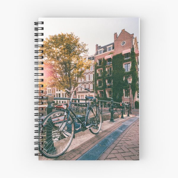 Item preview, Bicycle (bike) on a bridge in Amsterdam with Dutch house covered green plants during sunset designed and sold by michieldros.