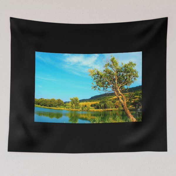 Item preview, Scene with a green tree hanging above the waters of the lake with vegetation on its shores and Marche hills in the background designed and sold by Kristina Drozd.