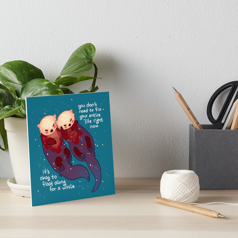 "It's Okay to Float Along For a While" Hand Holding Otters Art Board Print