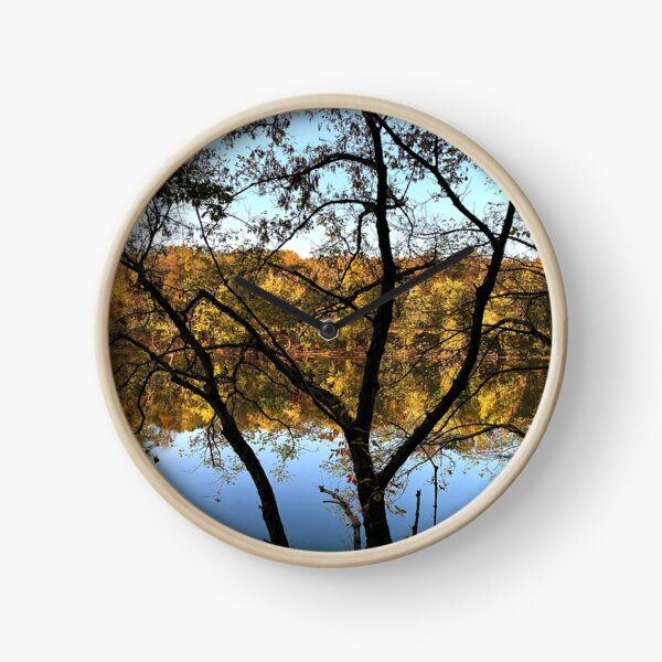 Reflection of trees in river at sunset Clock
