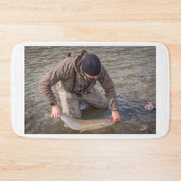 Item preview, An angler unhooking a fly from a steelhead in the morning spring sun designed and sold by SnapTPhotograph.