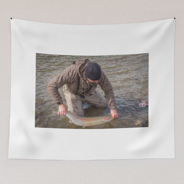 Item preview, An angler unhooking a fly from a steelhead in the morning spring sun designed and sold by SnapTPhotograph.