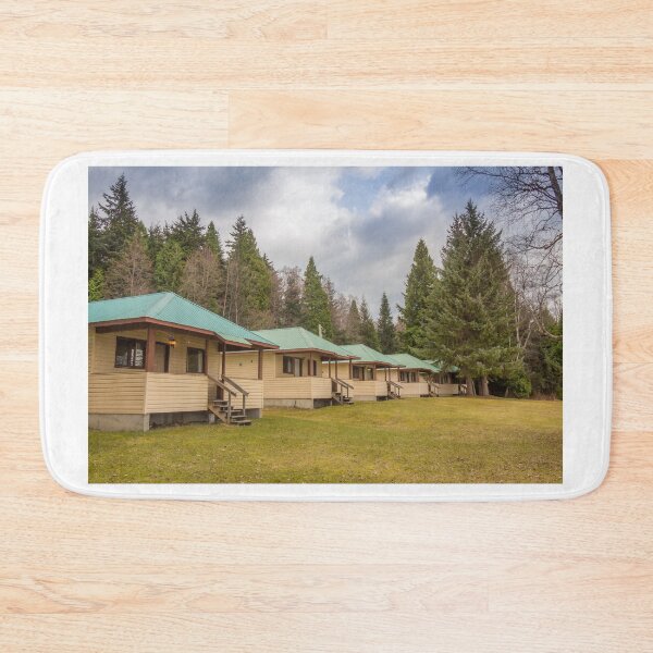 Item preview, A row of cabins set in woodland with dark clouds above designed and sold by SnapTPhotograph.
