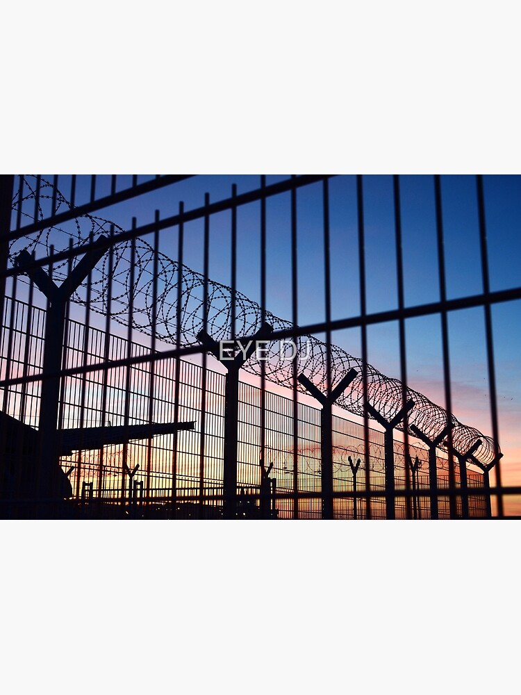 View through a barbed wire fence with beautiful colourful sunset sky in Dieppe France by iDJPhotography
