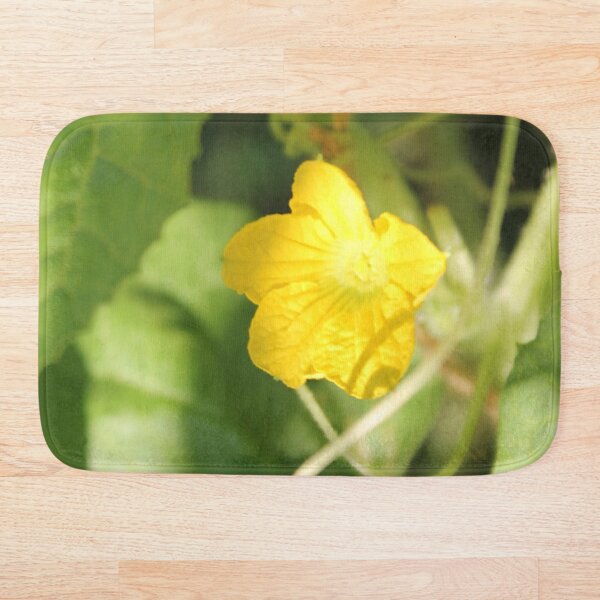Yellow unnamed flower on a background of green leaves Bath Mat