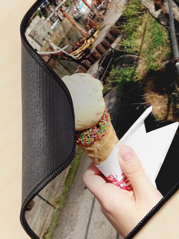Alternate view of Person holding an ice cream cone near a sailboat and an old building, sunny day with clouds in the sky Mouse Pad
