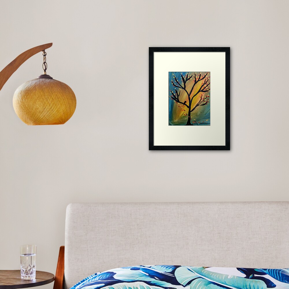 Black bird in the tree as the wind blows leaves off the tree  Framed Art Print