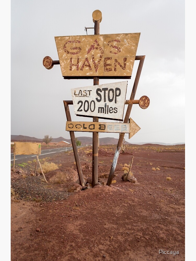 Tall vintage gas sign standing in the desert by Piccaya