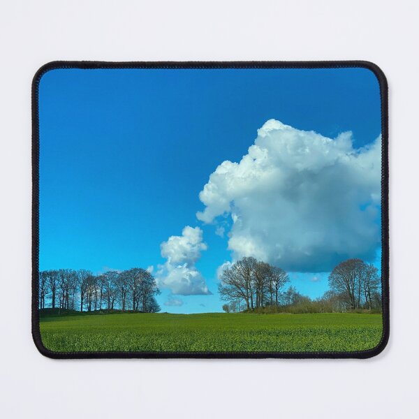Item preview, Puffy white cloud in a blue sky with trees on a green hill on Rügen Island, Germany designed and sold by Michael Brewer.