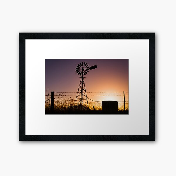 Classic Australian windmill on farmland silhouetted at sunset. Framed Art Print