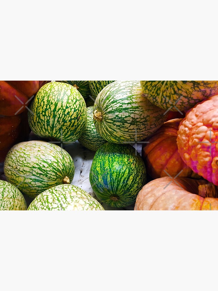 "A pile of melons, pumpkin and squash on a market stall with orange and