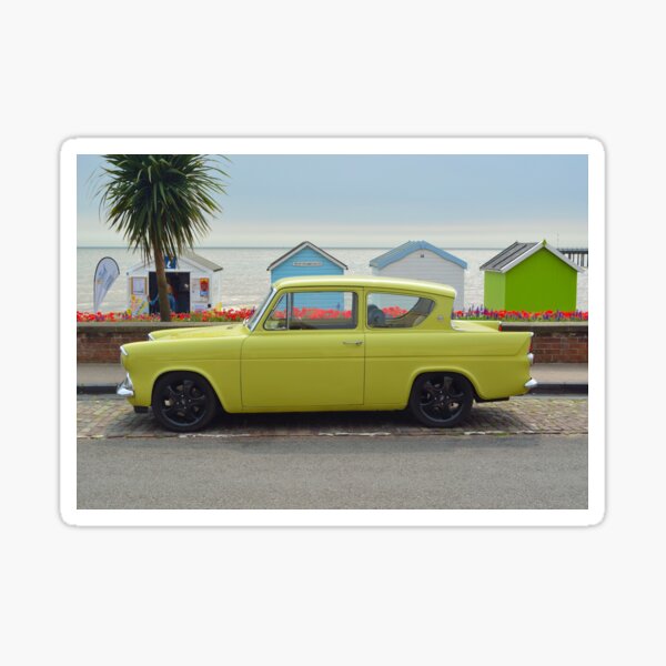 "Classic Yellow Ford Anglia motor car on seafront road in front of