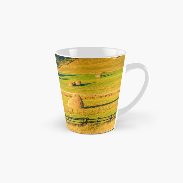 haystacks and a trees on a hillside meadow Tall Mug