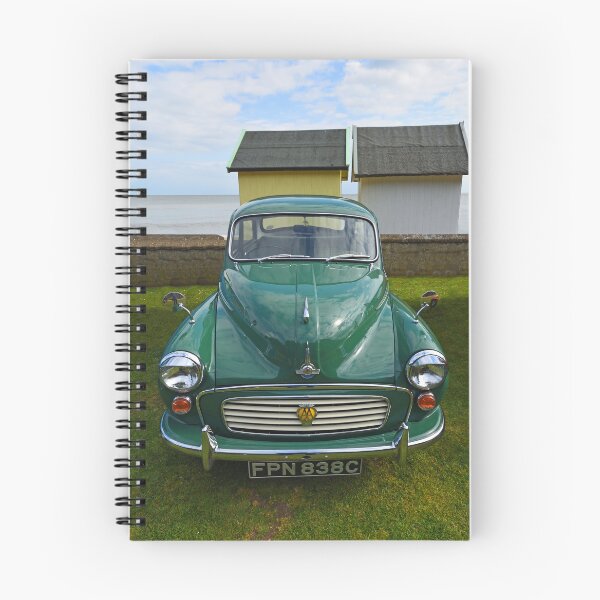 Item preview, Classic Green Morris Minor with AA Badge parked with beach huts and ocean in background. designed and sold by Umdash919.