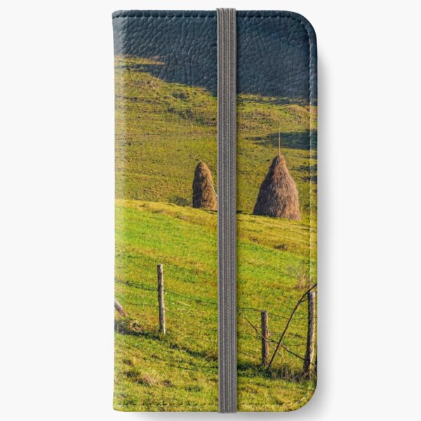 hay stacks behind the fence on rural field iPhone Wallet