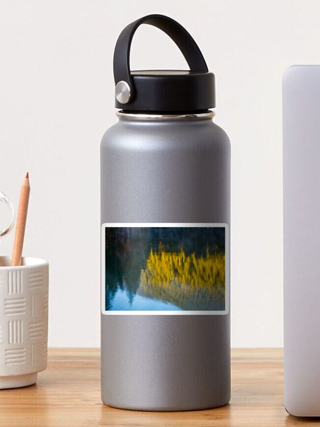 Thumbnail 1 of 3, Sticker, lake surface reflecting spruce forest at sunrise designed and sold by mike-pellinni.