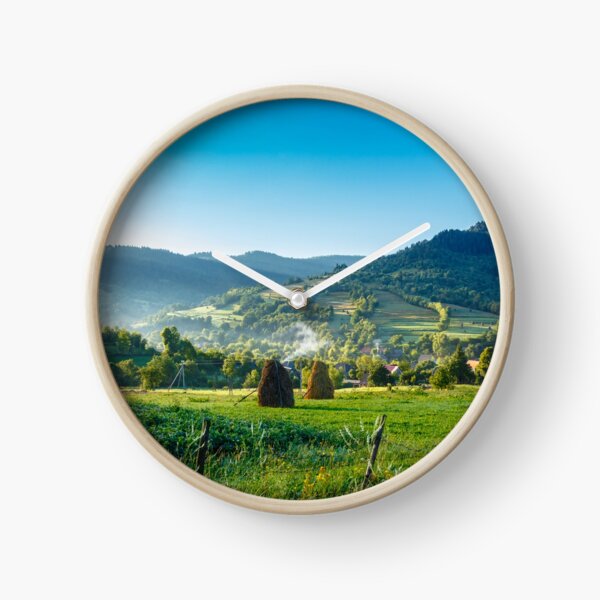 field with haystack on hillside in mountains Clock