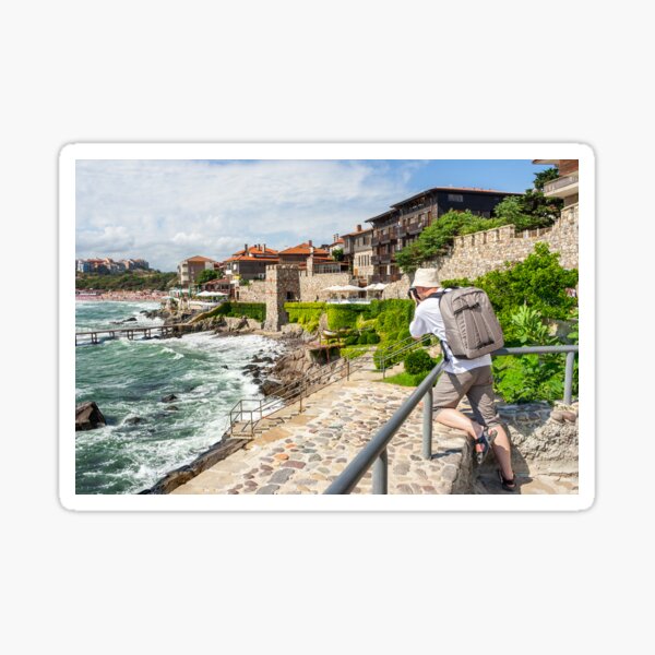 photographer with backpack shooting in old town Sozopol near sea in summer Sticker