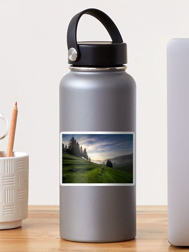 Thumbnail 1 of 3, Sticker, fir trees on meadow between hillsides in fog before sunrise designed and sold by mike-pellinni.