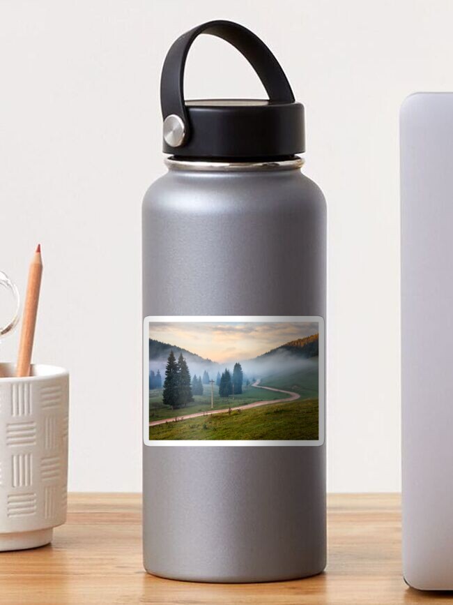 Thumbnail 1 of 3, Sticker, road near fir forest in foggy mountains at sunrise designed and sold by mike-pellinni.