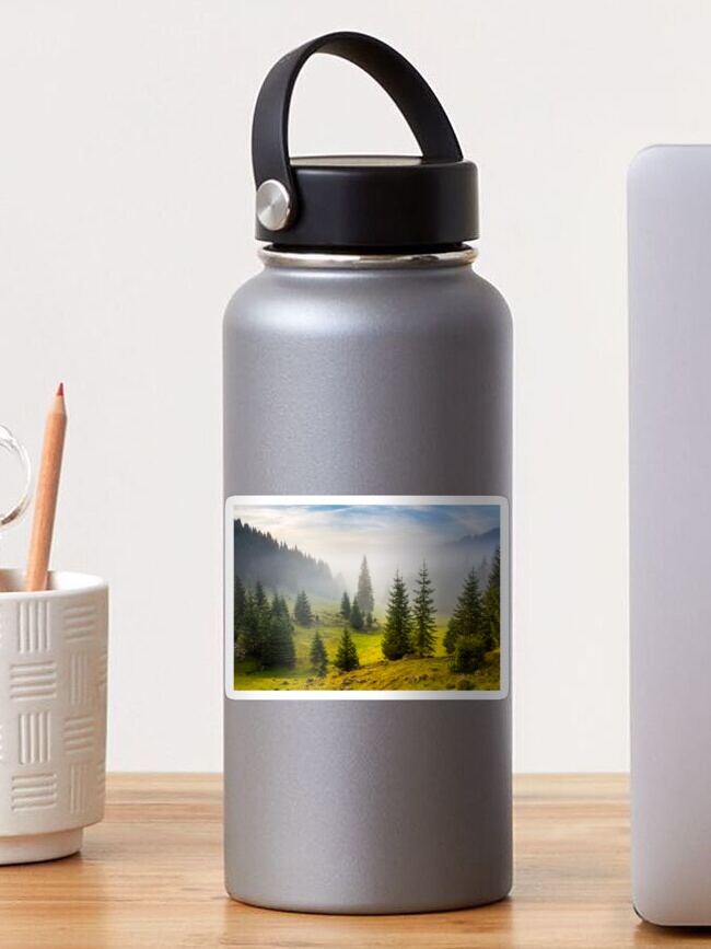 Thumbnail 1 of 3, Sticker, fir trees on meadow between hillsides in fog before sunrise designed and sold by mike-pellinni.