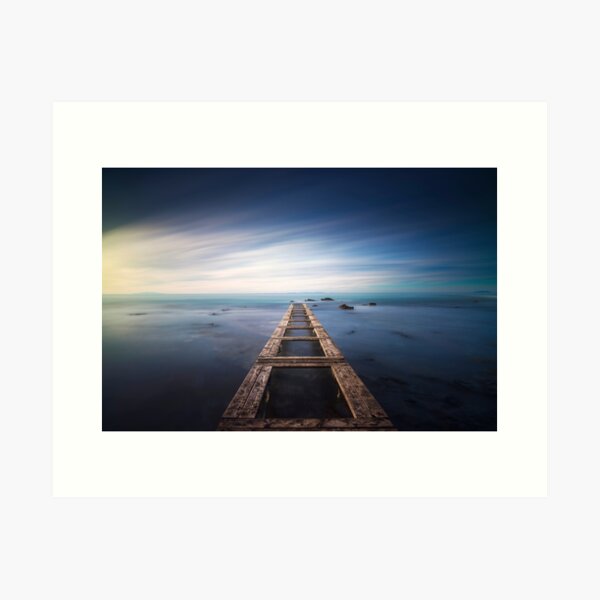 Wooden pier remains in a blue sea. Long Exposure. Art Print