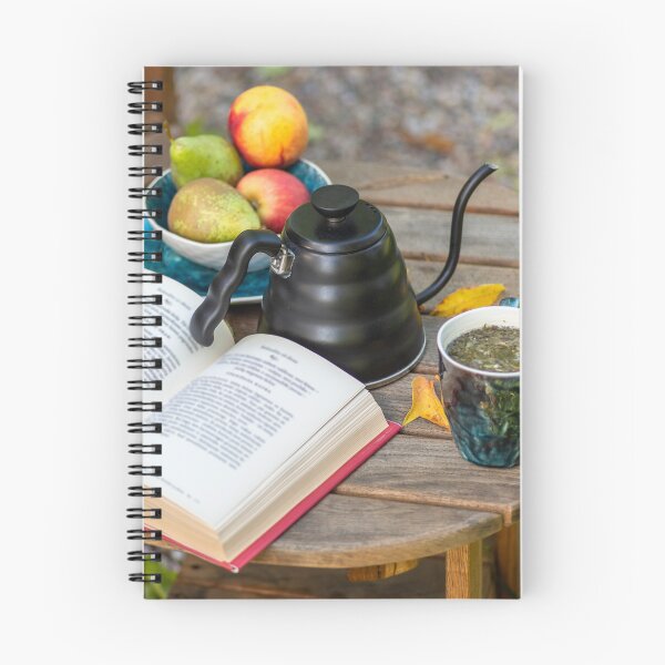 Item preview, An open book, a kettle with a cup of tea, a plate with apples and pears, on a wooden table with comfortable armchair beside, outdoor in autumn. designed and sold by AlbertMi.