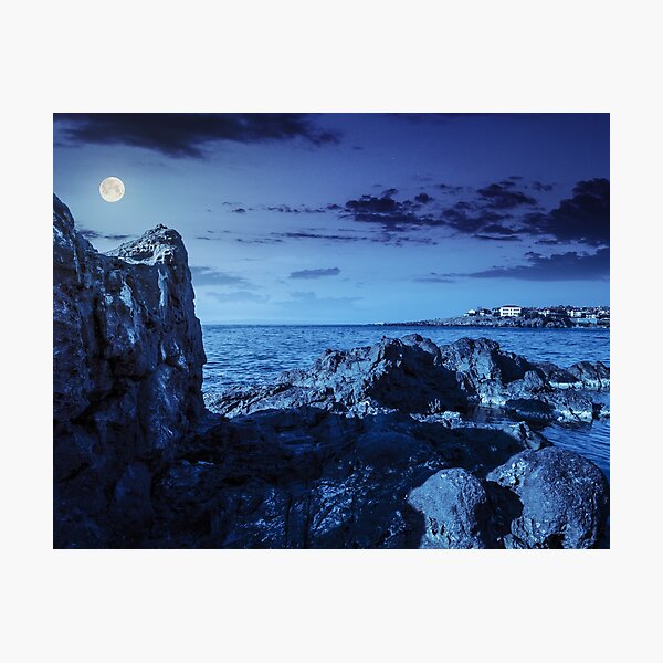 sea bay with boulders and old city at night Photographic Print