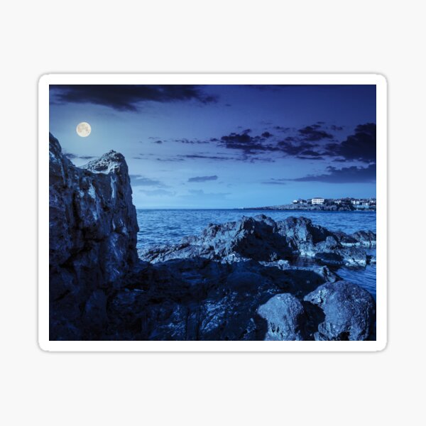 sea bay with boulders and old city at night Sticker