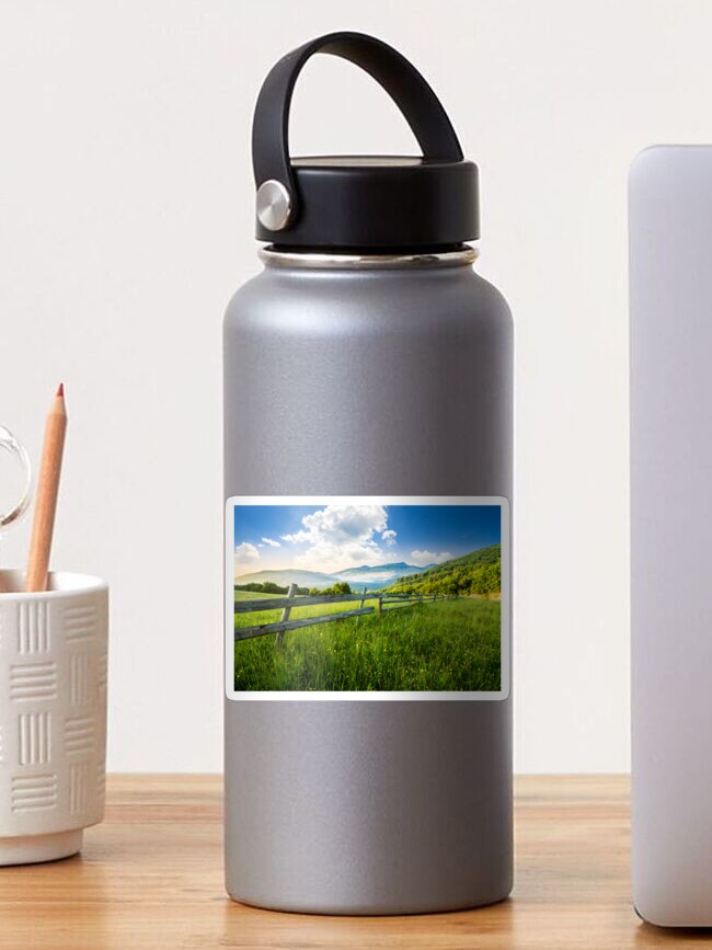 Thumbnail 1 of 3, Sticker, fence on hillside meadow in mountains at sunrise designed and sold by mike-pellinni.