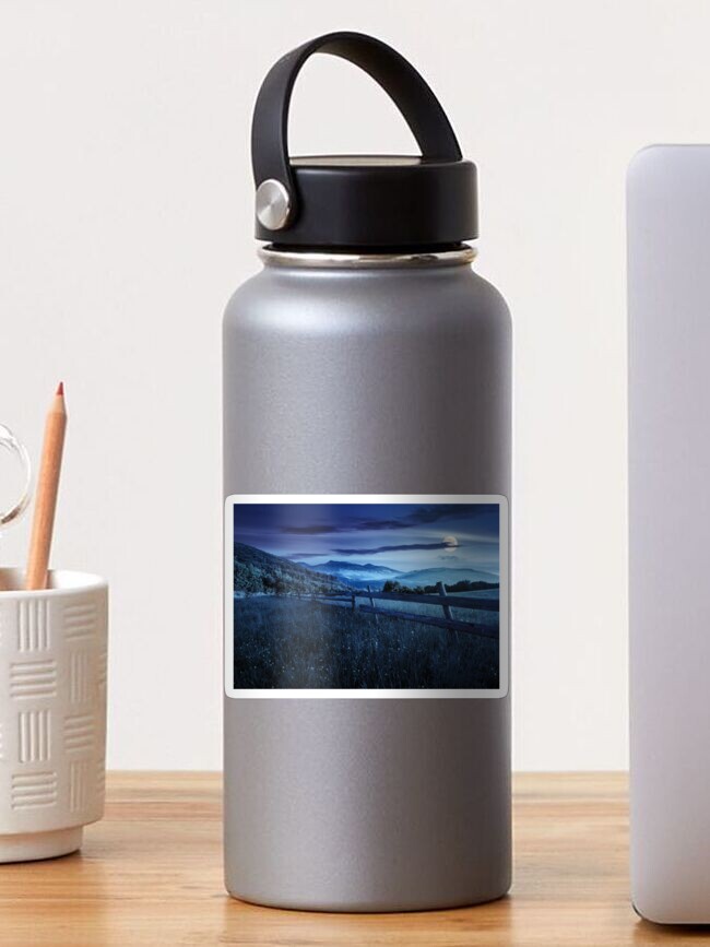 Thumbnail 1 of 3, Sticker, fence on hillside meadow in mountains at night designed and sold by mike-pellinni.