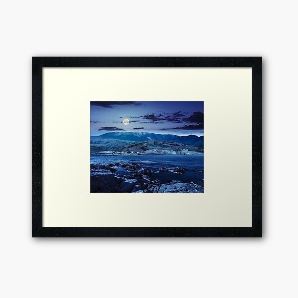 village near lake in mountains at night Framed Art Print