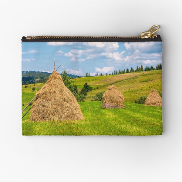 haystacks in a row on a grassy field Zipper Pouch