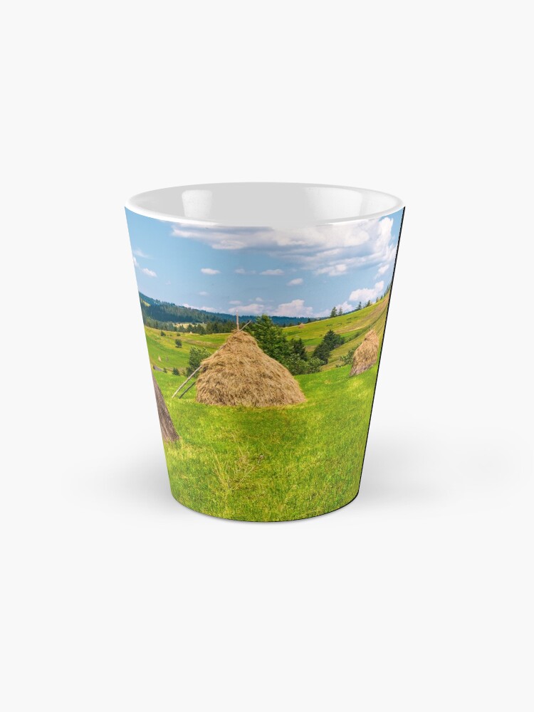 Alternate view of haystacks in a row on a grassy field Mug