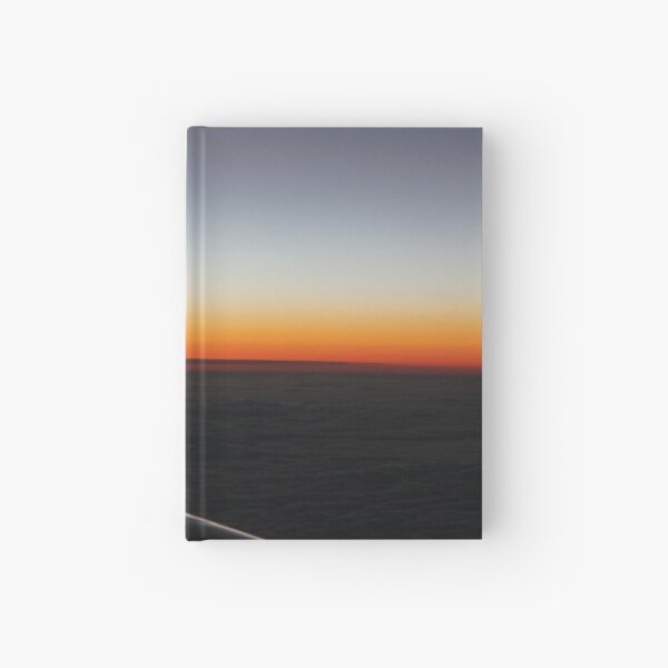The setting sun, evening dawn, pink clouds from the side of the plane. Hardcover Journal