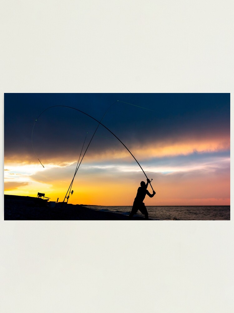 Fisherman cast fishing rods on the seashore at a dramatic sunset. |  Photographic Print