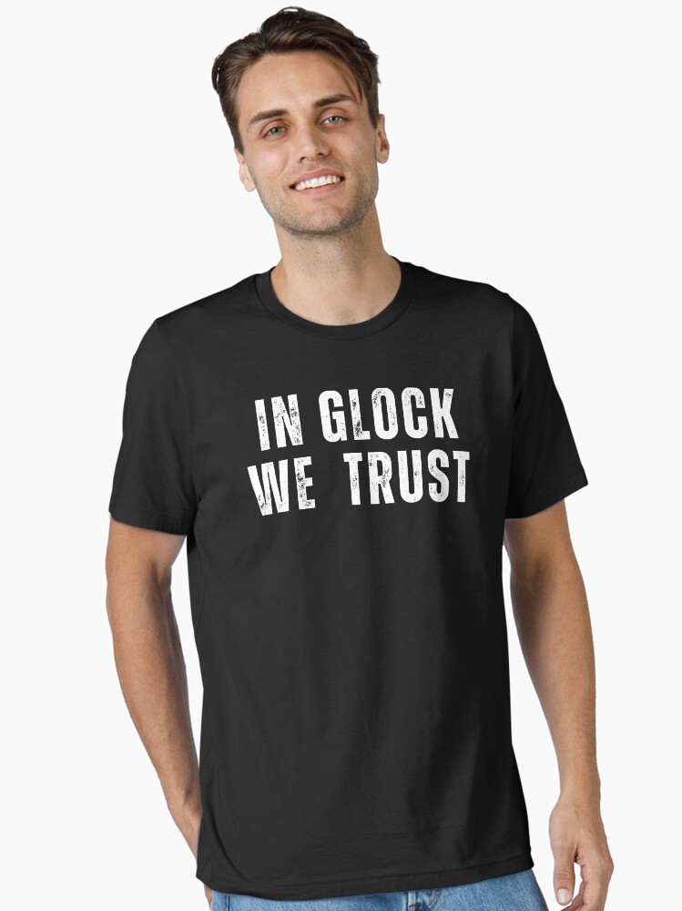 Imagen 1 de 7, Camiseta esencial con la obra en glock confiamos, diseñada y vendida por anninoart.