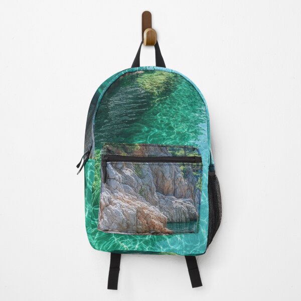 Item preview, Serene turquoise water flows through rocky cliffs into a secluded cove surrounded by lush vegetation and mountains under a bright sun. designed and sold by Jerhus.