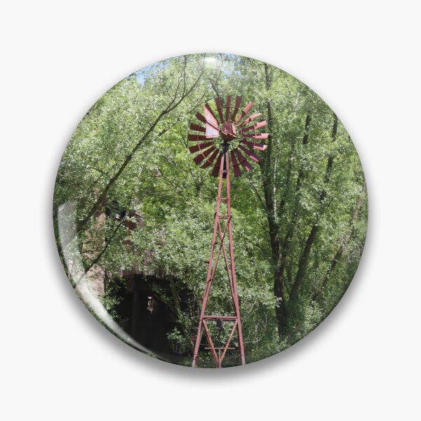 Item preview, Old fashioned metal windmill for natural energy conversion antique windmill near water and green forest behind designed and sold by Jacobs-Media.