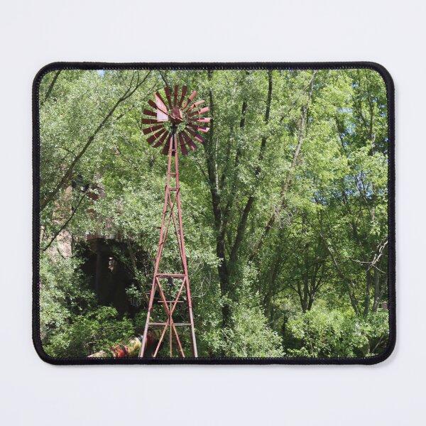 Item preview, Old fashioned metal windmill for natural energy conversion antique windmill near water and green forest behind designed and sold by Jacobs-Media.