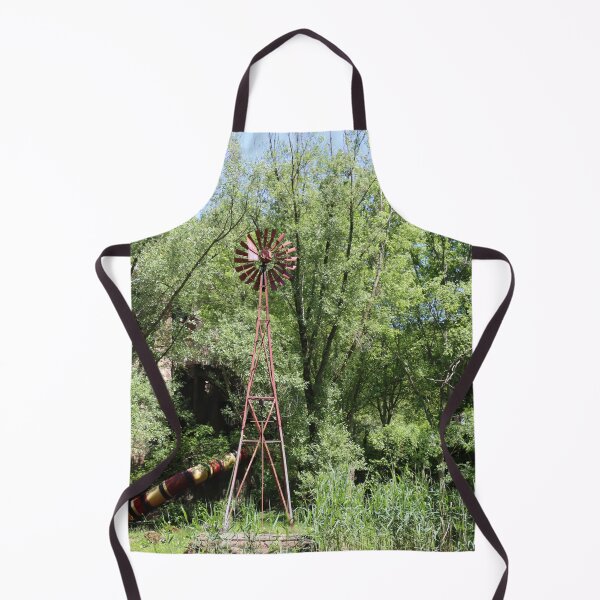 Item preview, Old fashioned metal windmill for natural energy conversion antique windmill near water and green forest behind designed and sold by Jacobs-Media.