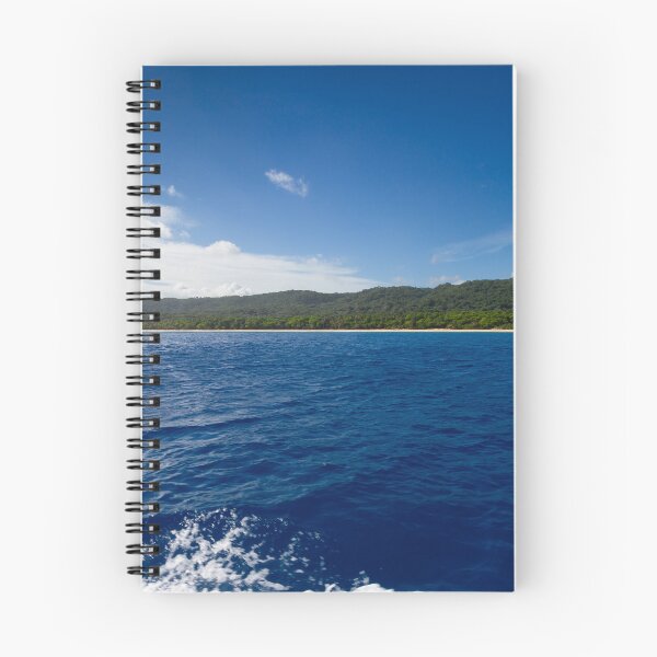 Item preview, A vast expanse of deep blue ocean meets a lush green shoreline under a clear, bright sky designed and sold by EyezWatchin.